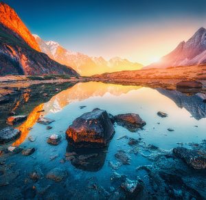 Mountains with illuminated peaks stones in mountain lake at sunset containing